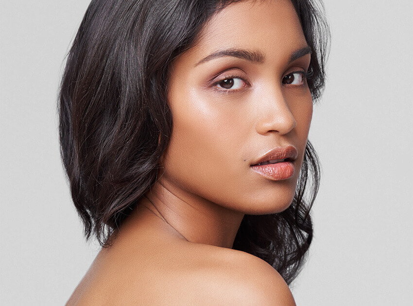 headshot of woman with bare shoulders looking over her shoulder