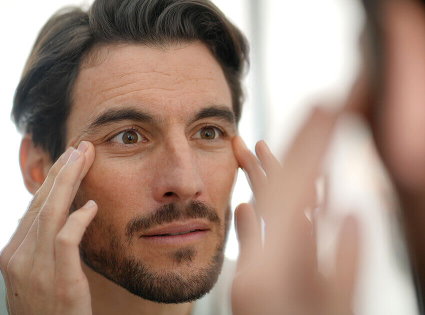 headshot of man self examining his eyes and face