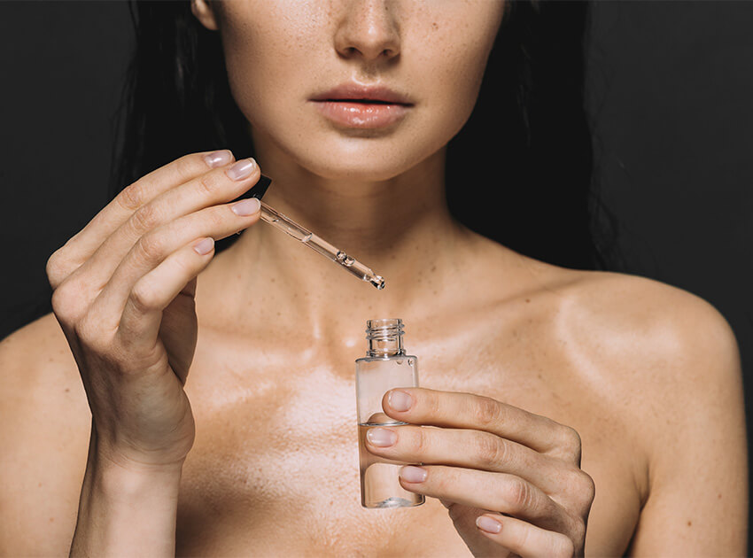 upper body shot of woman with bare shoulders filling up a bottle with clear liquid